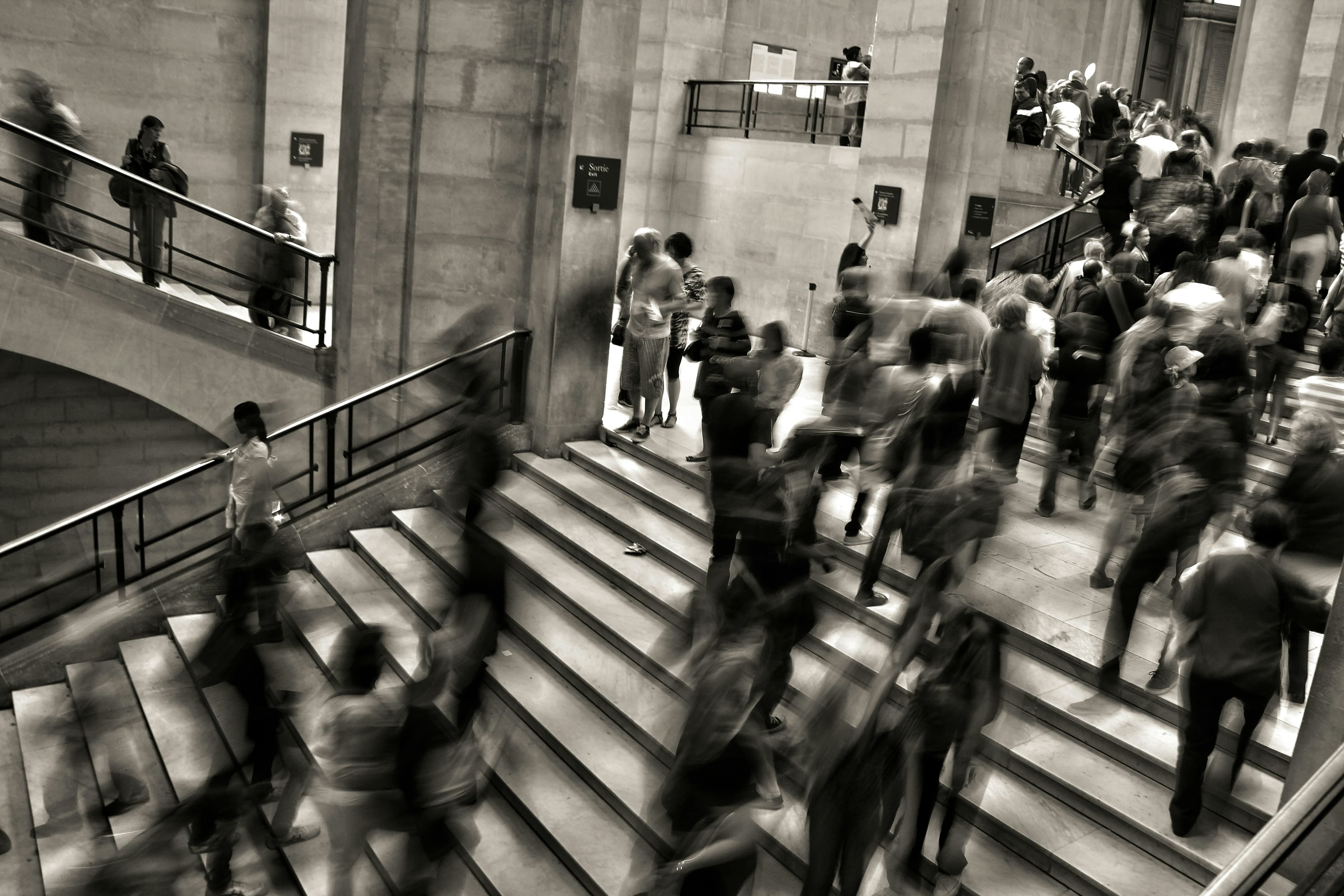 People moving through a large institutional staircase in a black-and-white documentary photograph.